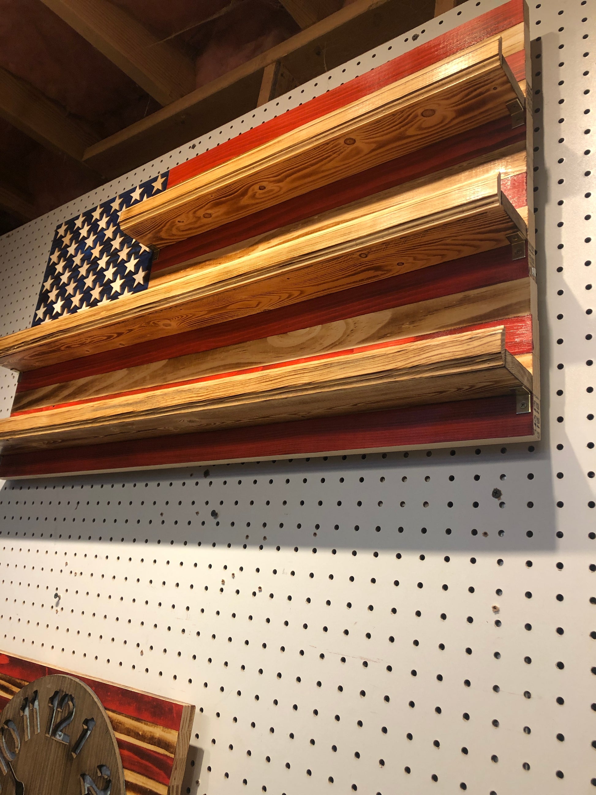 American flag shot glass holder display wall art made of wood with rustic finish mounted on a pegboard wall