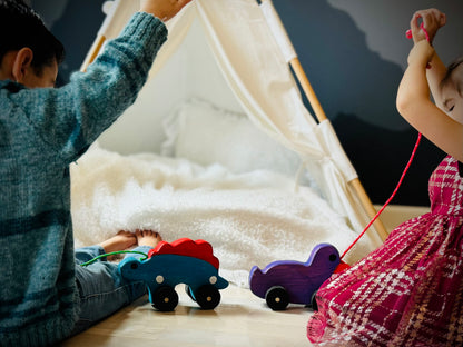 Children playing with a handcrafted dinosaur kids pull toy and a purple pull toy in a cozy room