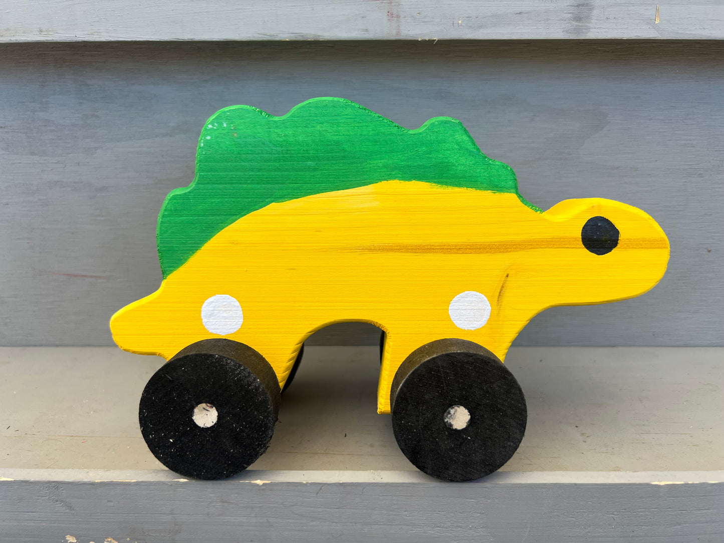 Handcrafted dinosaur kids pull toy in yellow and green with black wheels wooden design
