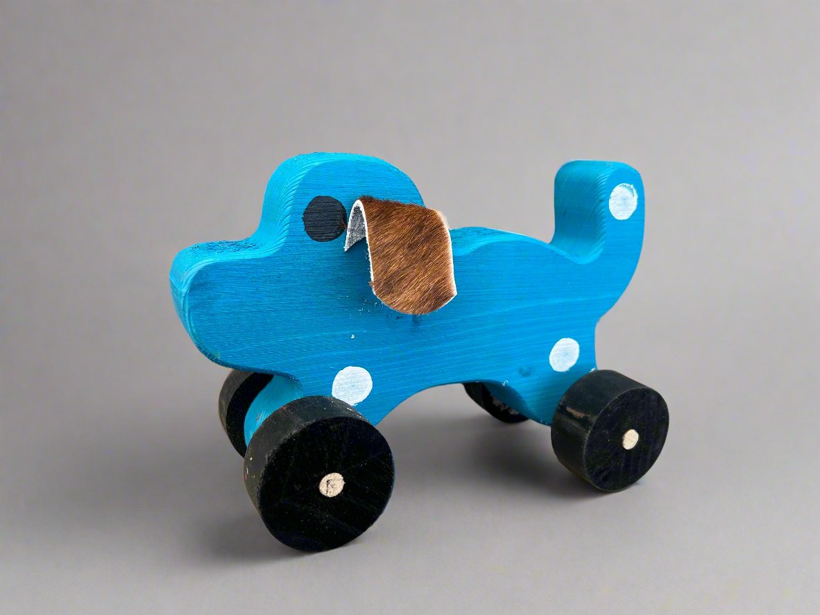Blue handmade wooden dog pull kids toy with black wheels and brown ear on gray background