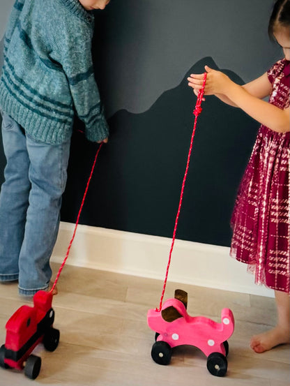 Children playing with handmade wooden dog pull kids toy and wooden train toy on wheels