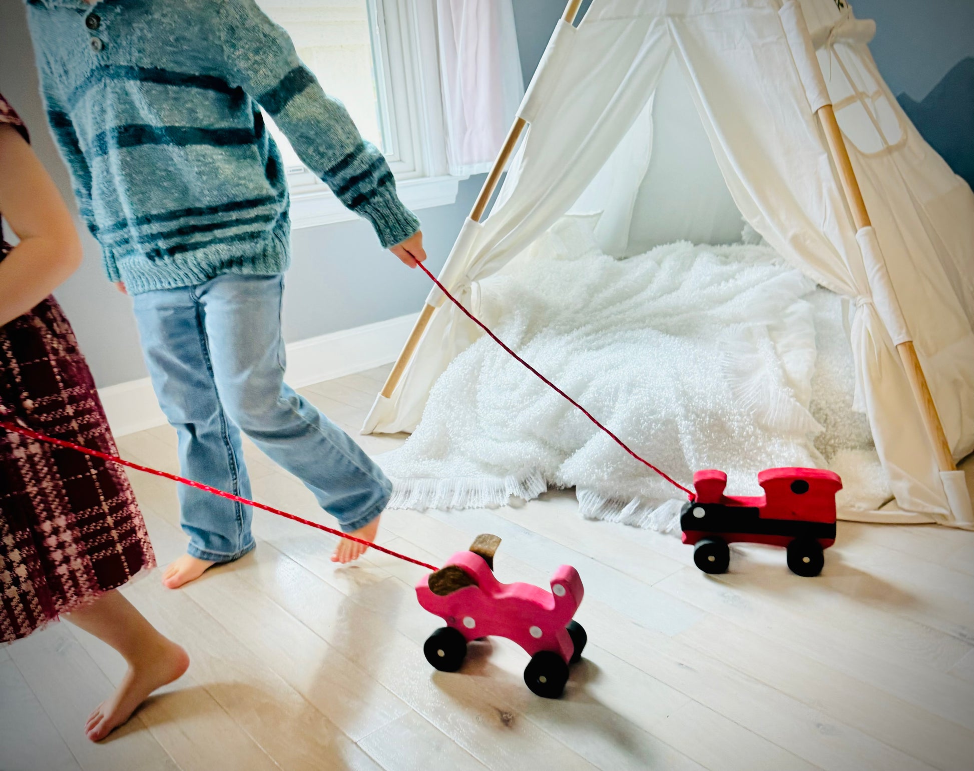 Children playing with handmade wooden dog pull kids toy on wheels in a cozy playroom