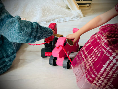 Children playing with a handmade wooden dog pull kids toy in bright pink color on wooden floor