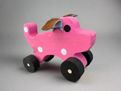 Handmade wooden dog pull kids toy in pink with black wheels and white spots