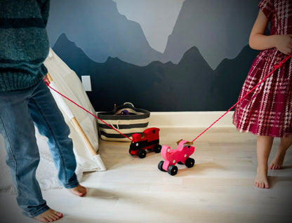 Children playing with handmade wooden dog pull kids toy in a cozy indoor setting