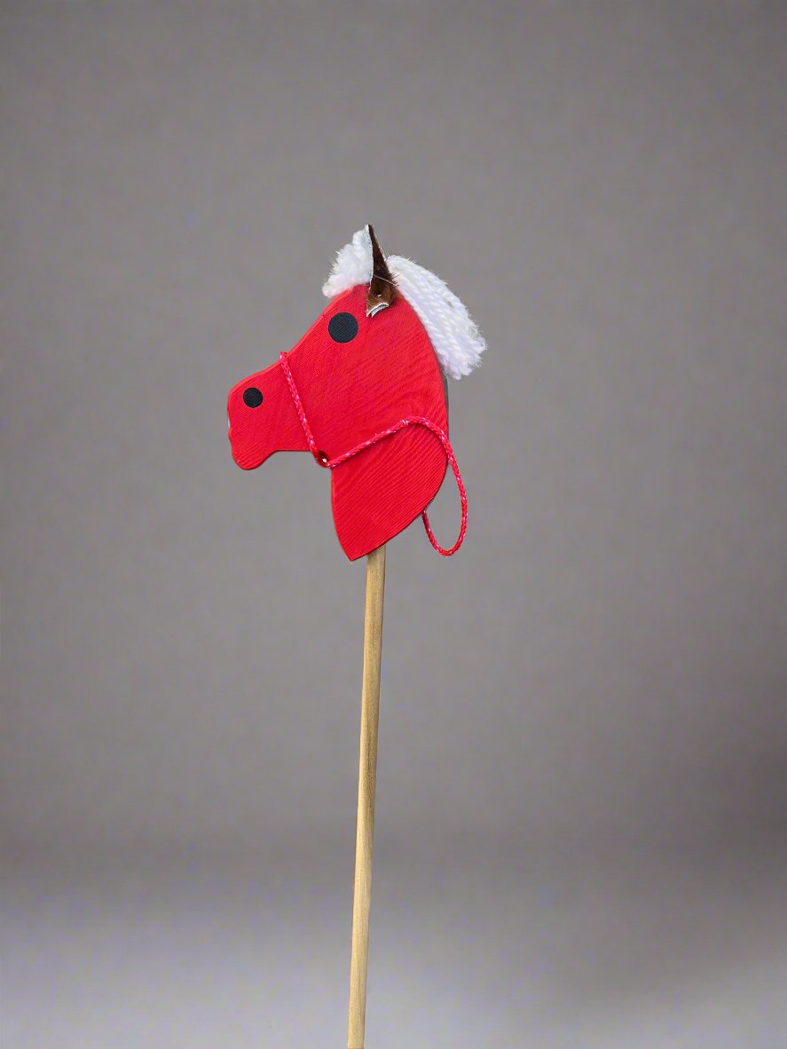 Red kids wooden hobby horses with white yarn mane on wooden stick against gray background