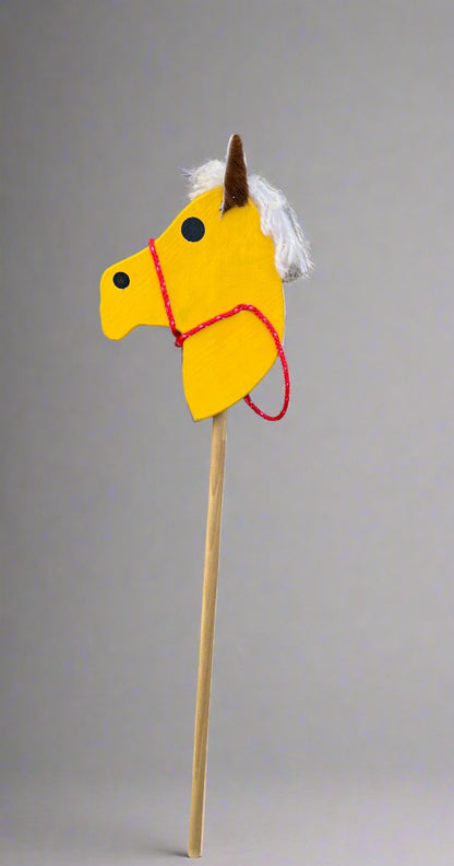 Yellow kids wooden hobby horses with white mane and red bridle on a wooden stick