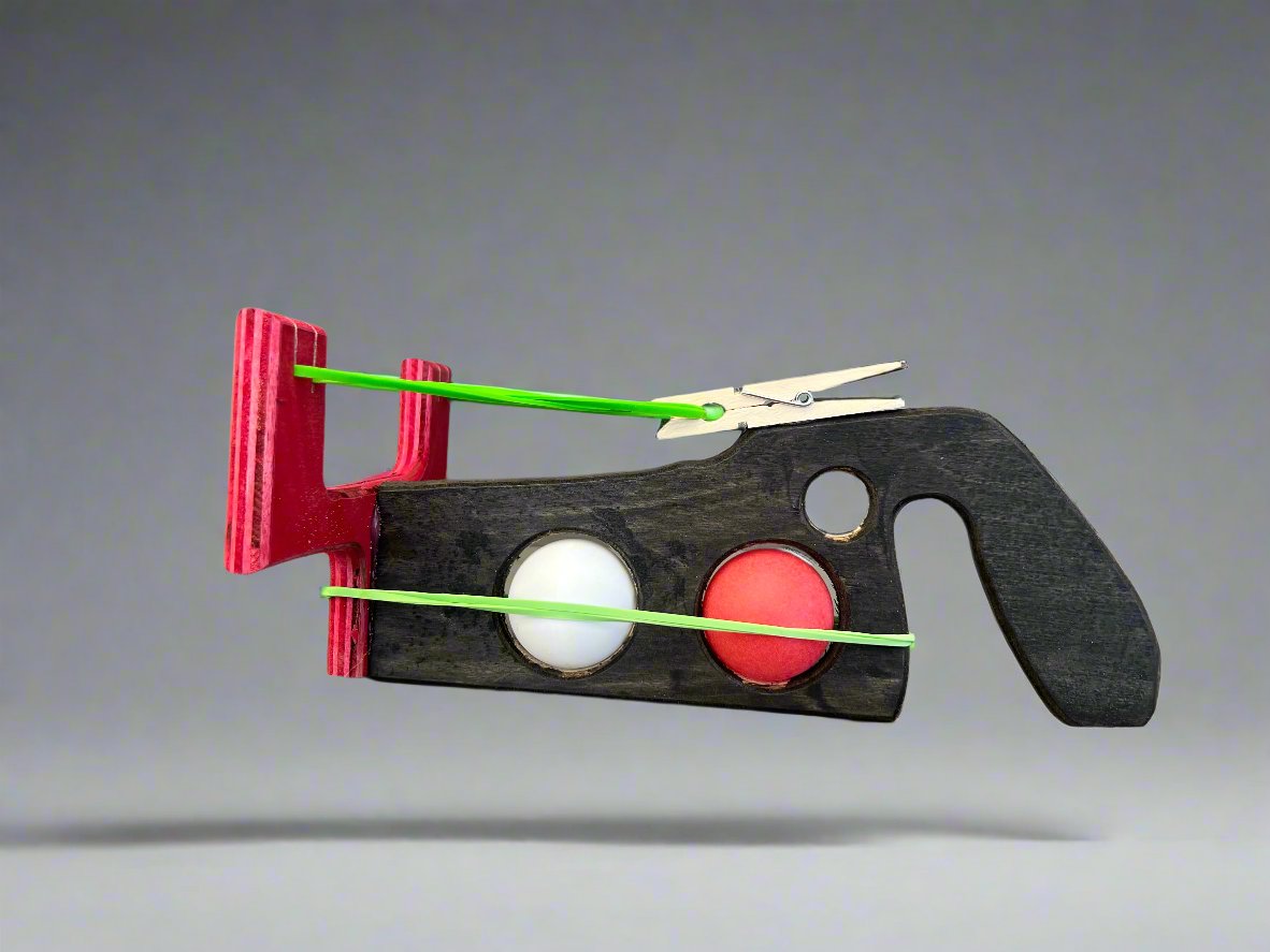 Kids wooden ping pong ball launcher with red and black wooden body and green rubber bands
