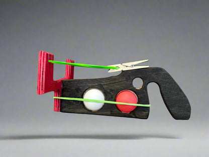 Kids wooden ping pong ball launcher with red and black wooden body and green rubber bands