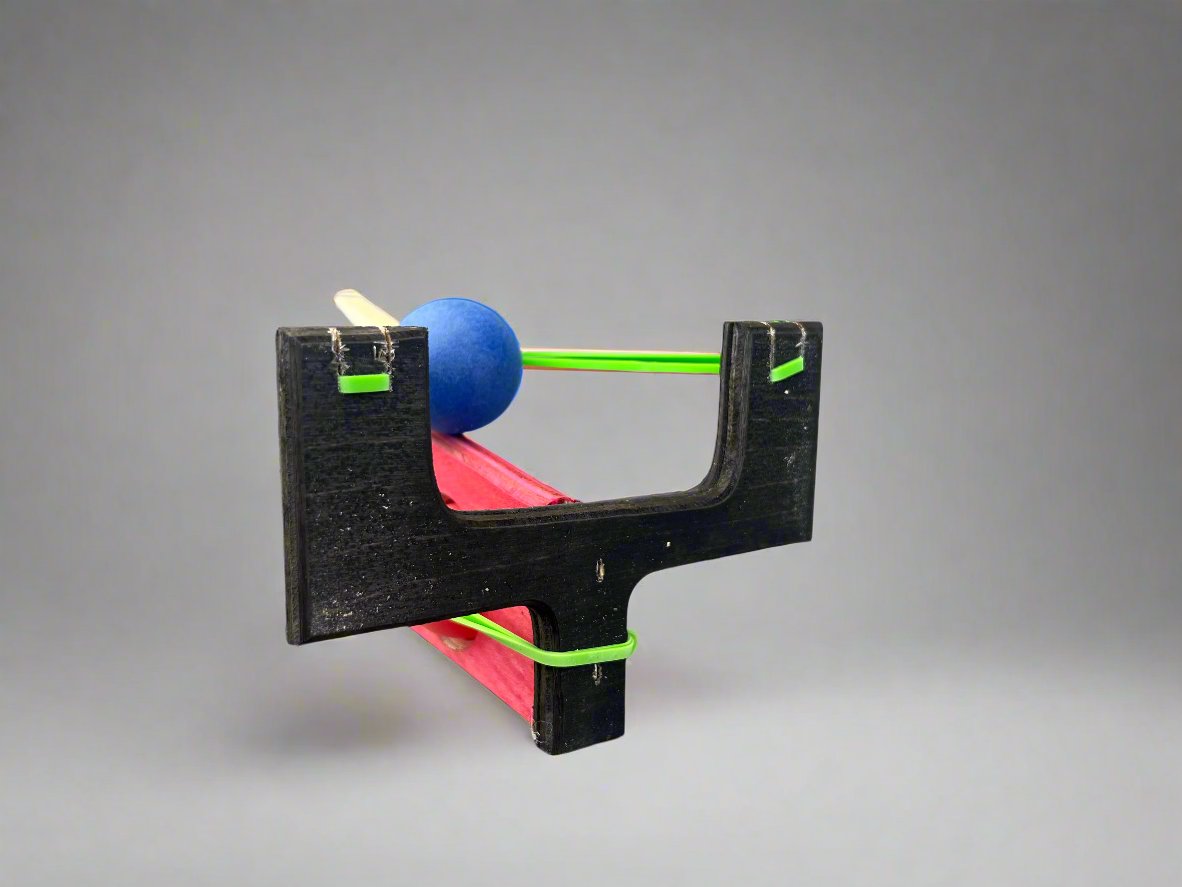 Kids wooden ping pong ball launcher in black and red with a blue ball loaded for play