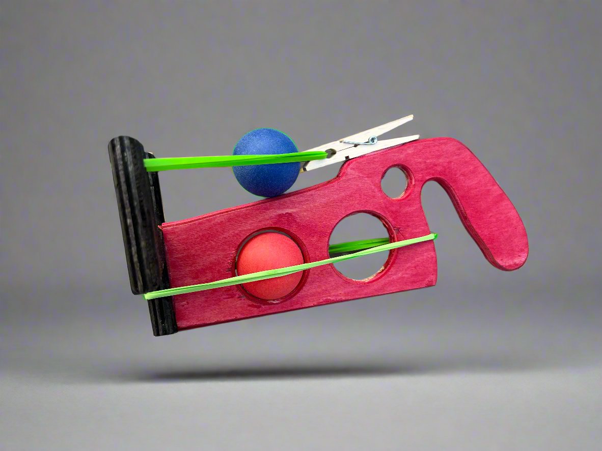 Kids wooden ping pong ball launcher in red with blue and red balls and green rubber bands
