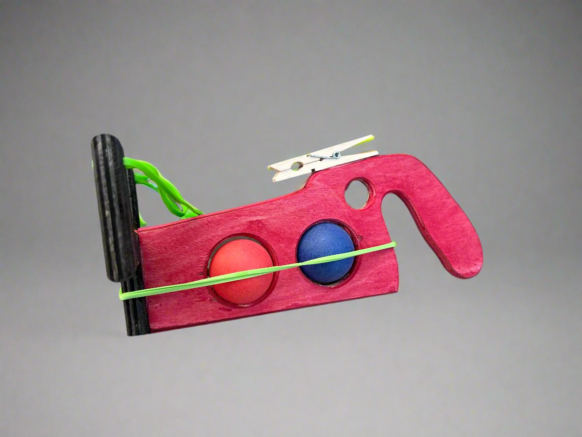Kids wooden ping pong ball launcher toy in red with blue and orange balls and rubber band mechanism