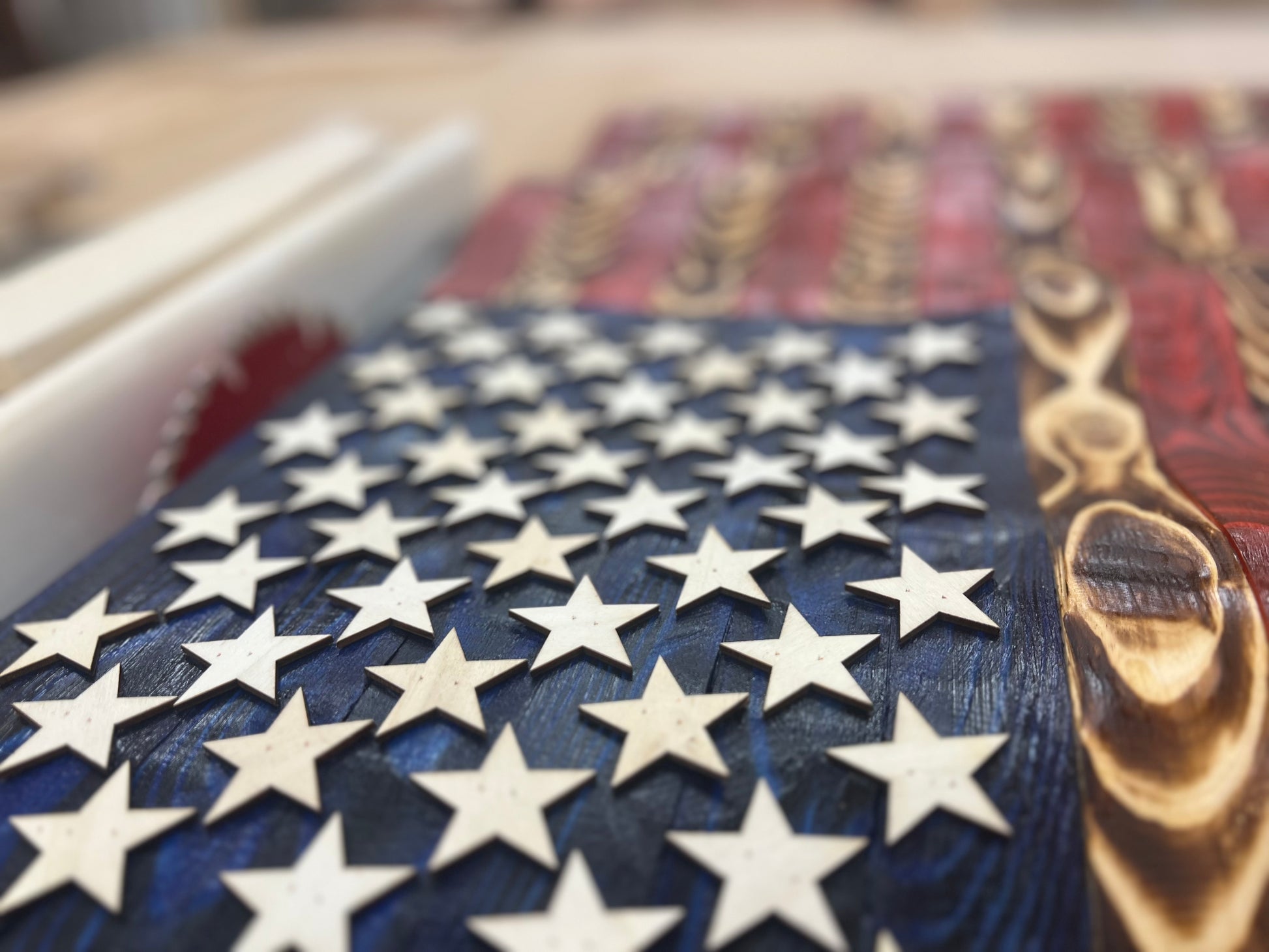 Close-up of rustic American flag wall art with wooden stars and distressed red and blue paint