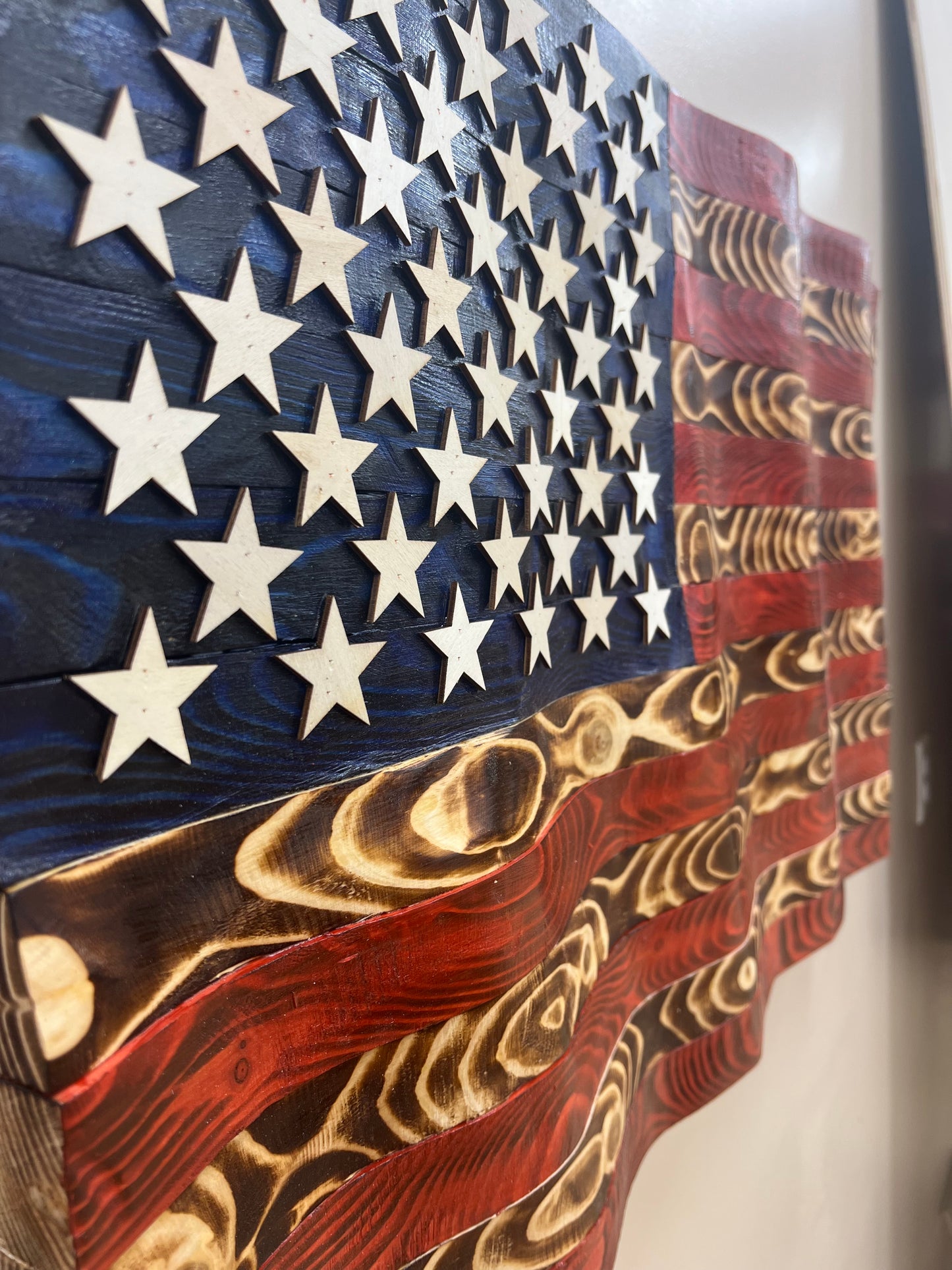 Rustic American flag wall art featuring carved wooden stars and stripes with a weathered finish
