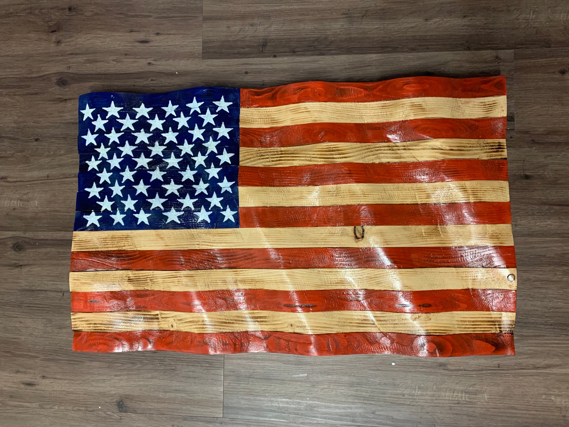 Rustic American flag wall art made of carved wood with distressed red, white, and blue paint