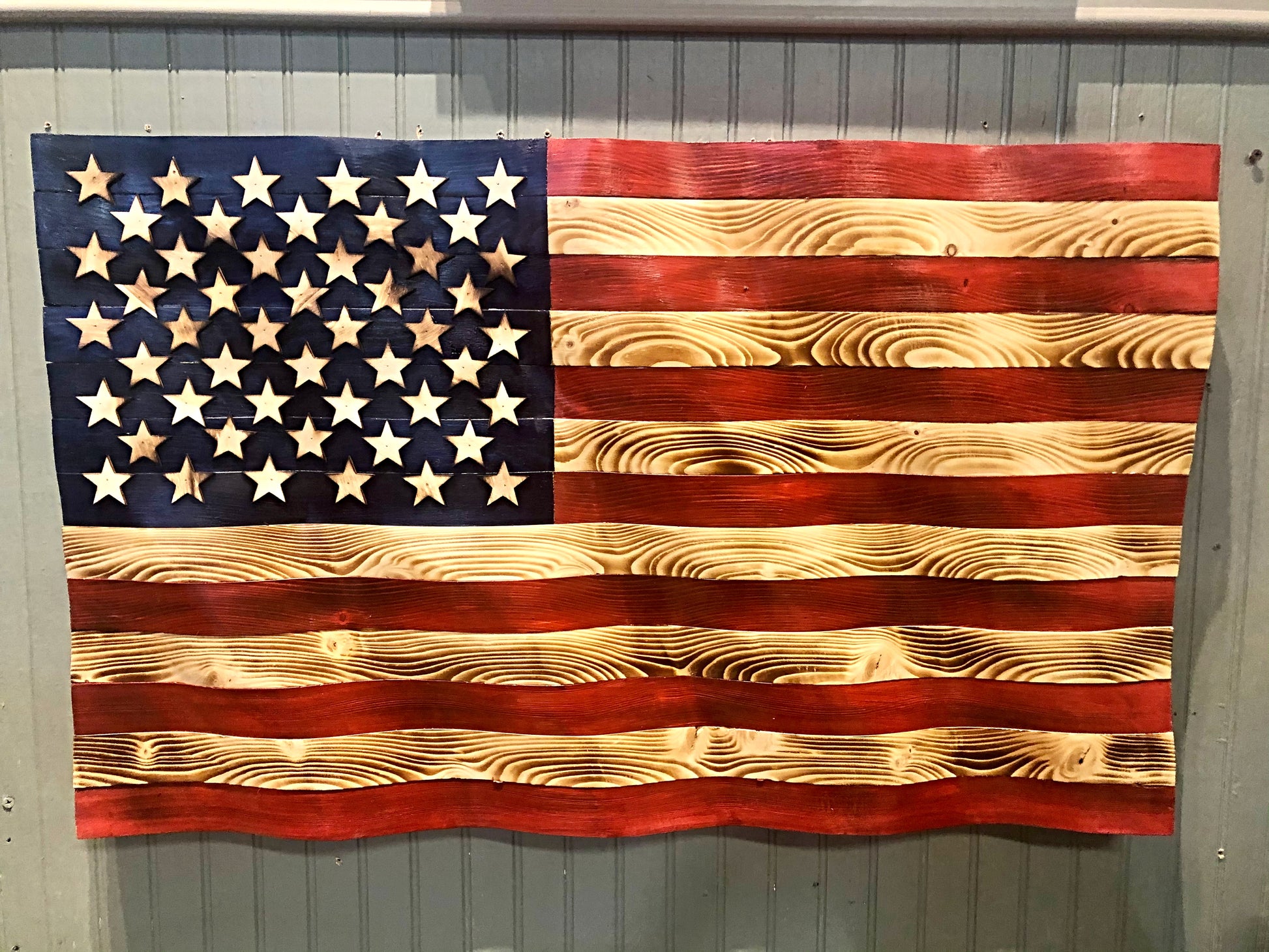 Rustic American flag wall art made of carved wood with natural grain and painted stars and stripes