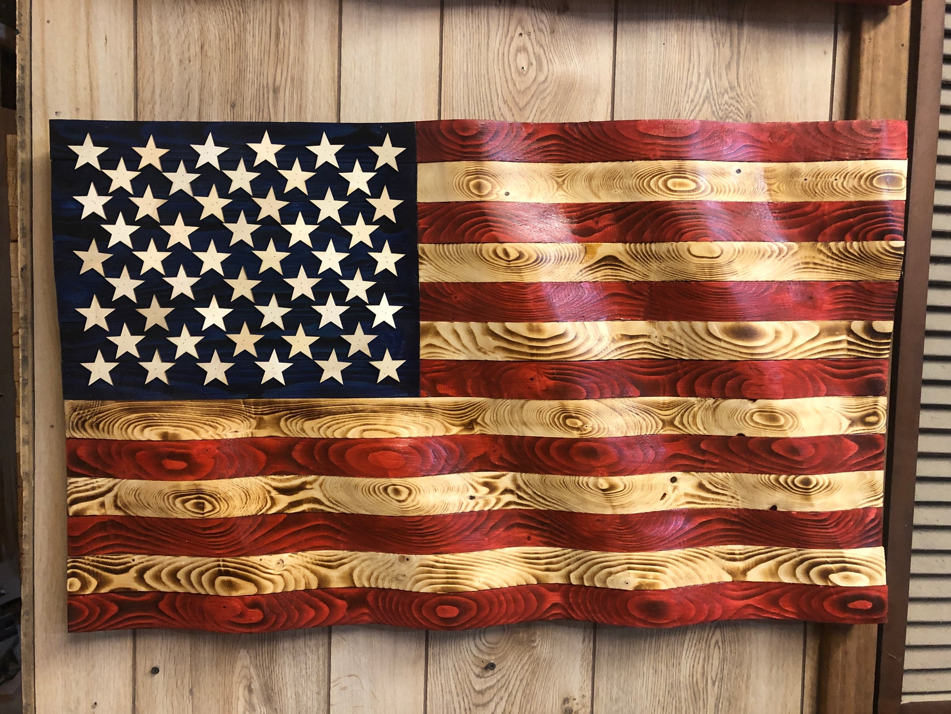 Rustic American flag wall art made of carved and stained wood with natural wood grain texture