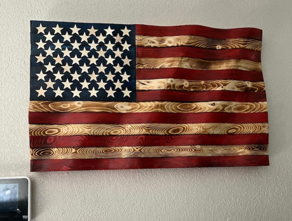 Rustic American flag wall art carved from wood with natural grain and distressed red, white, and blue colors