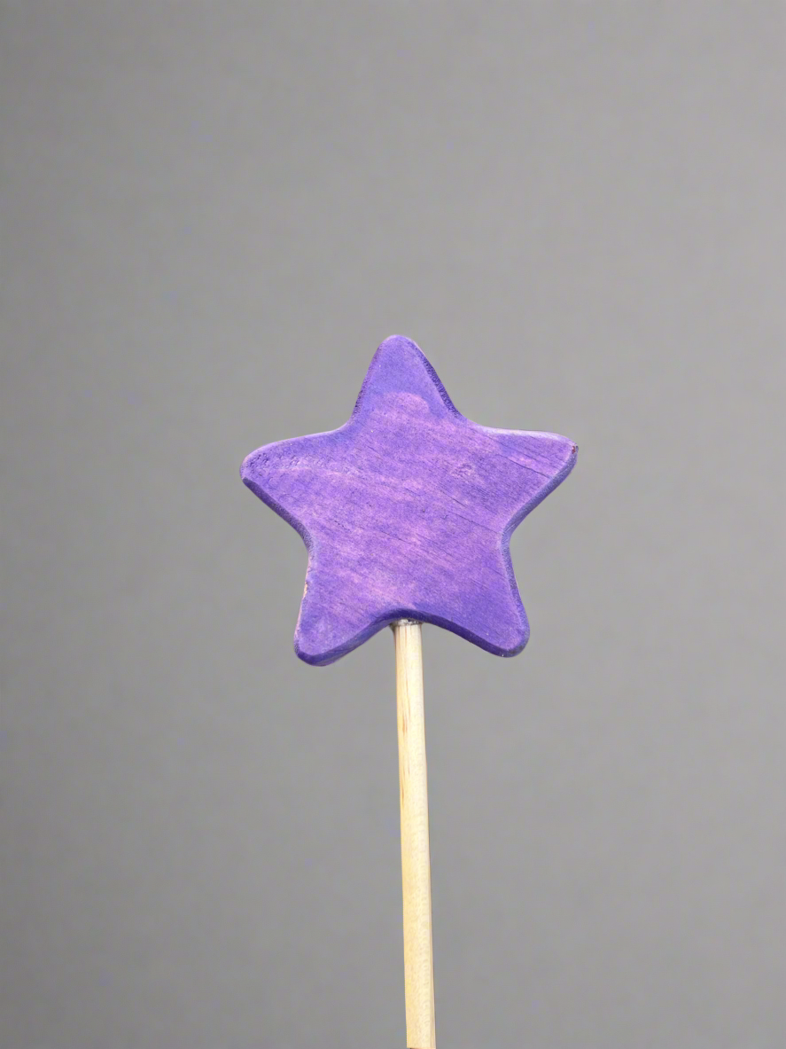 Purple star-shaped colorful wooden magic wand toy on a wooden stick against gray background