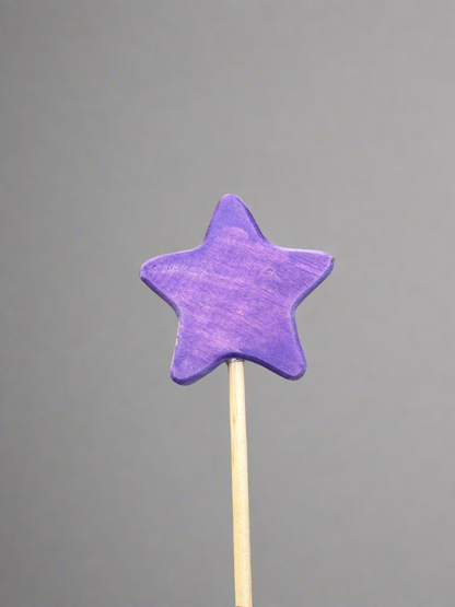 Purple star-shaped colorful wooden magic wand toy on a wooden stick against gray background