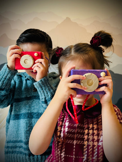Two children playing with colorful handmade kids wooden camera toys indoors