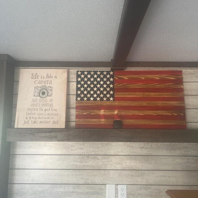 Wooden American Flag wall decor with rustic red, white, and blue finish displayed on a shelf