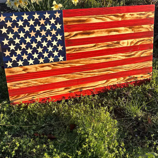 Handcrafted Wooden American Flag with carved stars and stripes displayed outdoors on grass