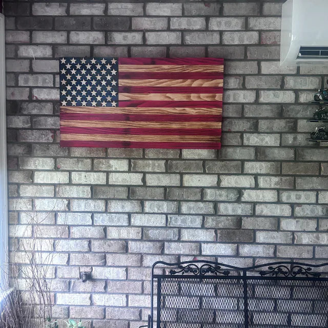 Wooden American Flag wall art mounted on gray brick wall above black metal decorative screen