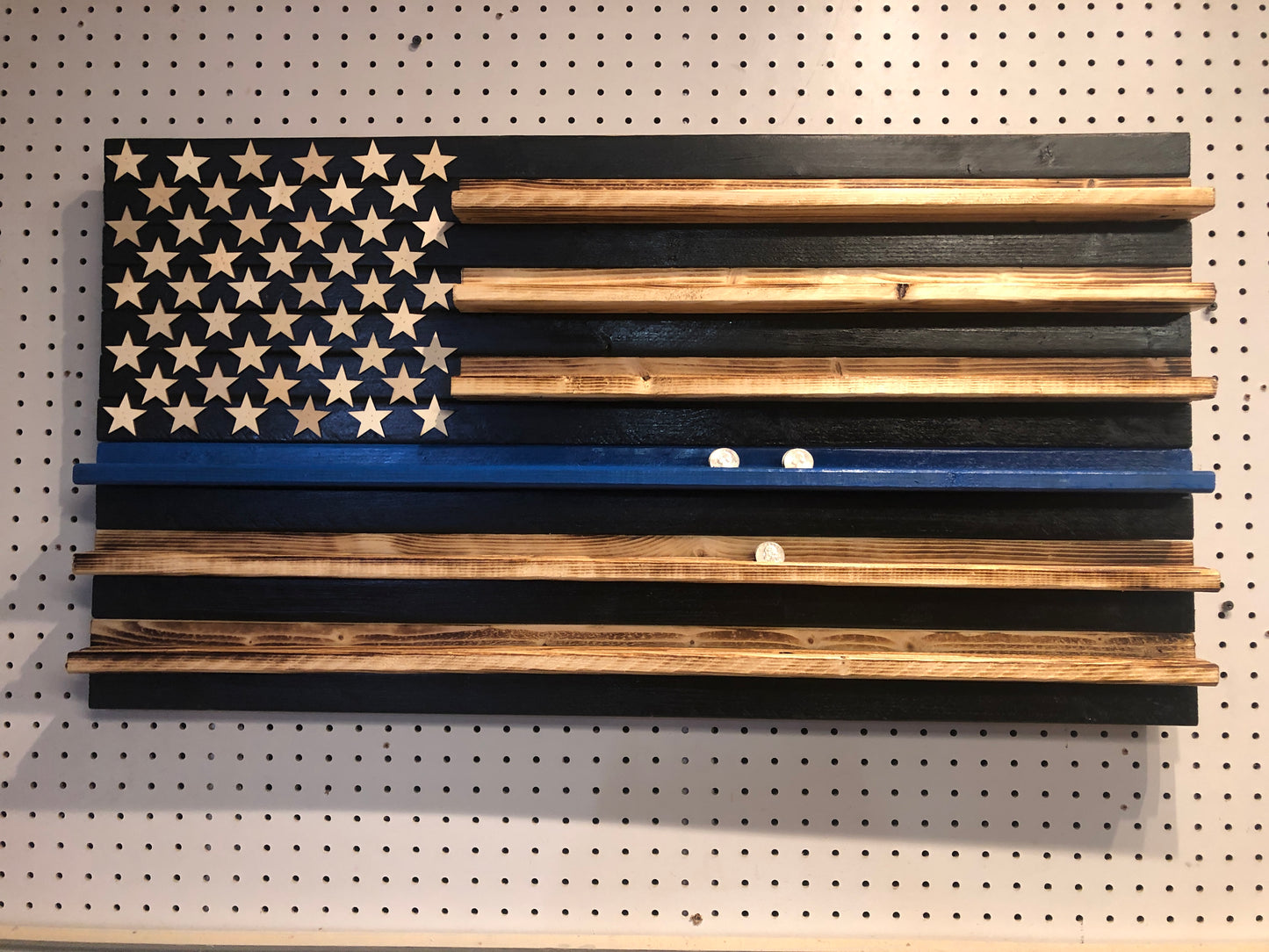 Wooden blue line flag coin holder display with natural wood stars and stripes on a pegboard background