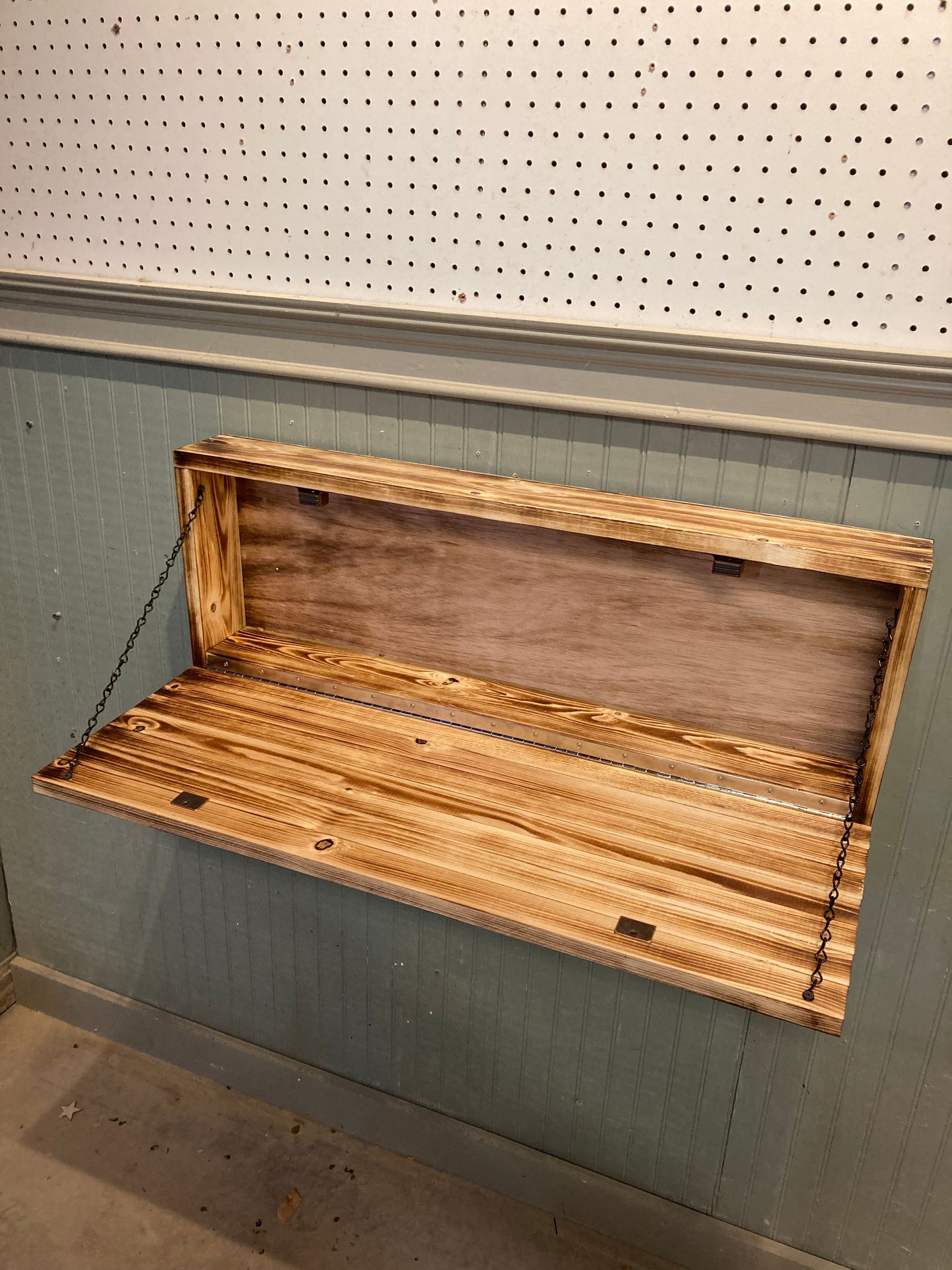 Wooden blue line front door box mounted on wall with open lid and chain supports
