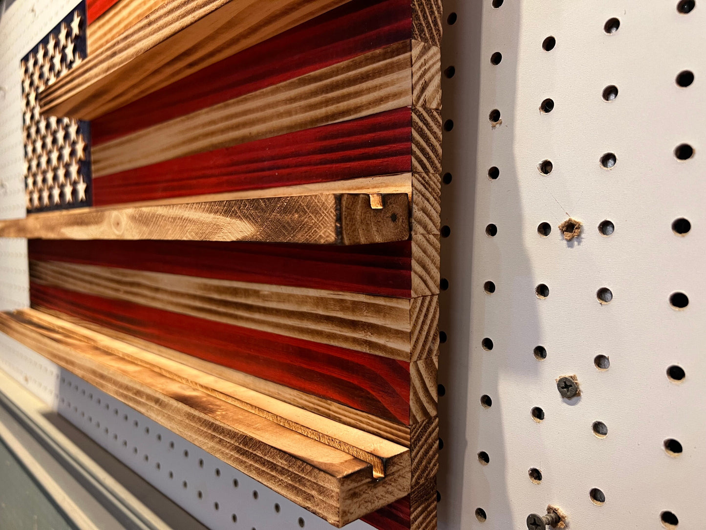 Wooden challenge coin holder flag wall art with deep shelves in red white and blue on pegboard