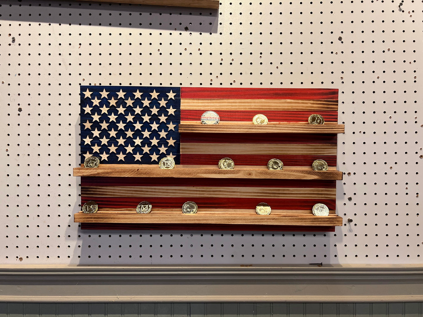 Wooden challenge coin holder flag wall art with American flag design and shelves holding challenge coins