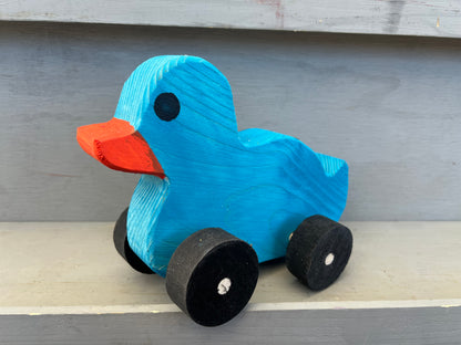 Blue wooden pull duck toy with orange beak and black wheels for children