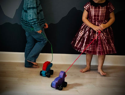 Children playing indoors with colorful wooden pull duck toys on wheels with strings