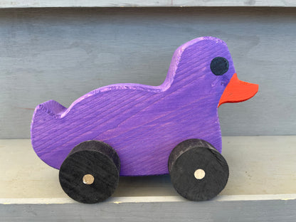 Purple wooden pull duck toy with black wheels and an orange beak for children