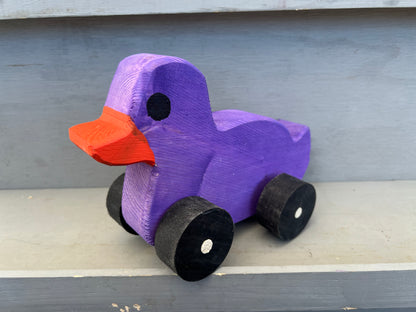 Purple wooden pull duck toy with orange beak and black wheels for children