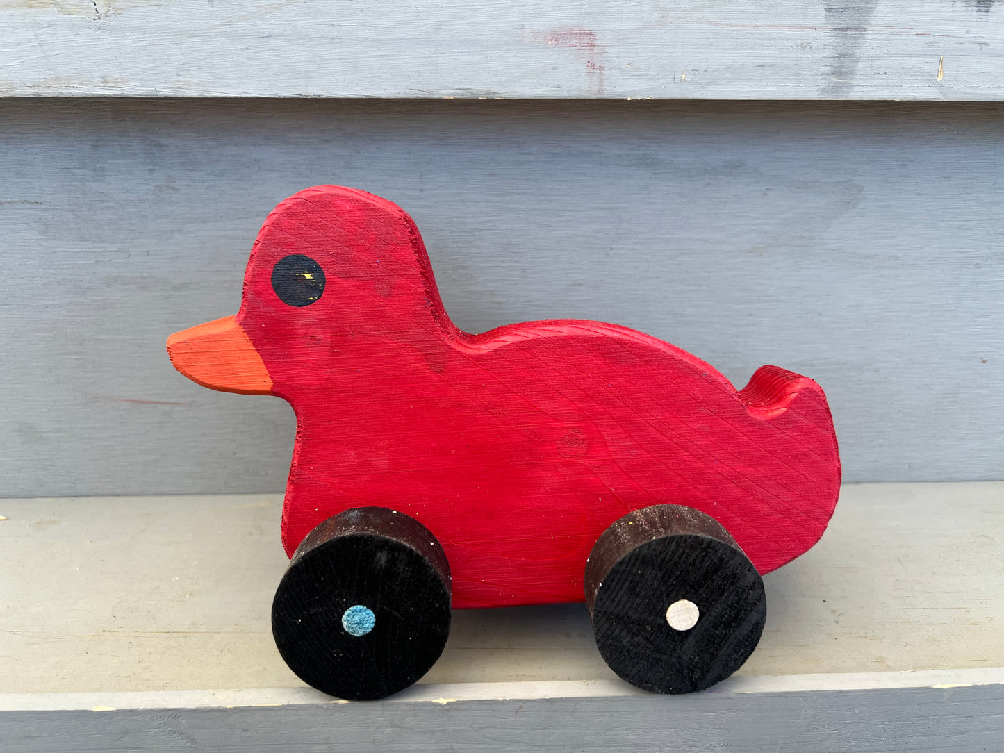 Red wooden pull duck toy with black wheels and orange beak perfect for children