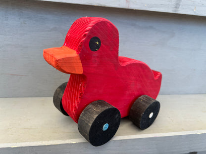 Red wooden pull duck toy with black wheels and orange beak for children’s playtime