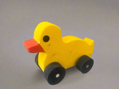 Yellow wooden pull duck toy with black wheels and orange beak on gray background